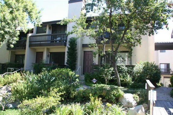 Front view of a multi-story residential building with balconies and a garden.