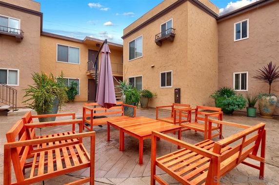Courtyard area with outdoor seating, surrounded by building walls and potted plants.