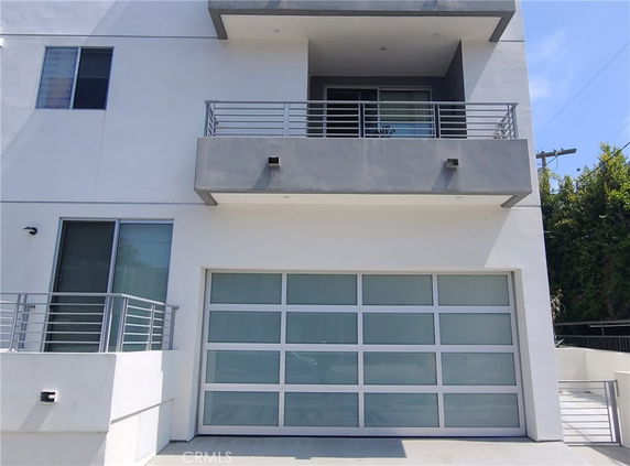 Front view of a modern multi-story house with a balcony and garage.