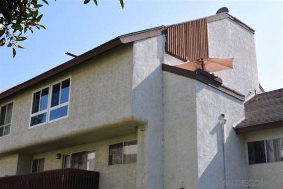 Side view of a two-story building with flat roof and several windows.
