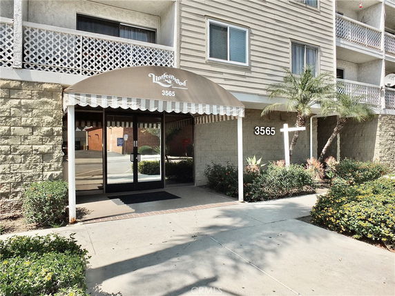 Front entrance of a multi-story building with an awning and glass doors.