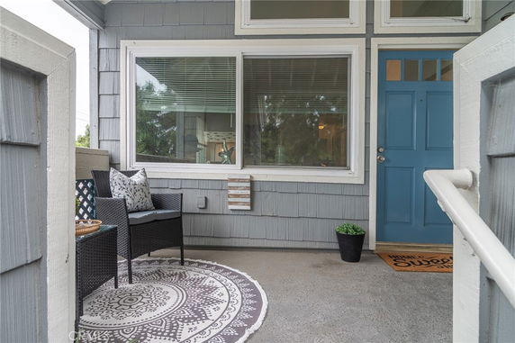 Front view of a house with a blue door and a window next to a small seating area.