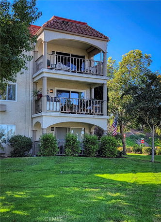 Front view of a multi-story building with balconies and red-tiled roof.
