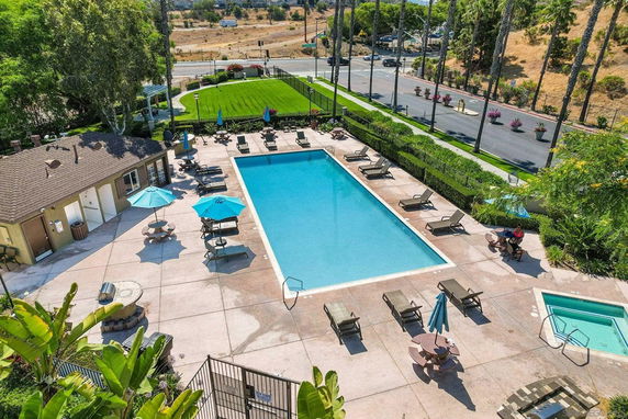 Aerial view of an outdoor swimming pool area with lounge chairs and umbrellas.