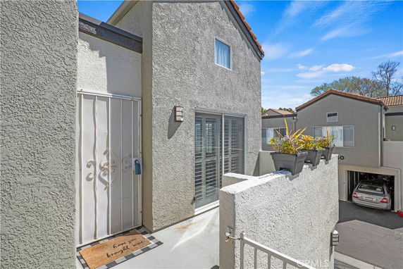 Exterior view of a multi-story residential building with a gated entry and balcony.