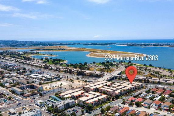 Aerial view showing a building complex with nearby roads and a large body of water in the distance.