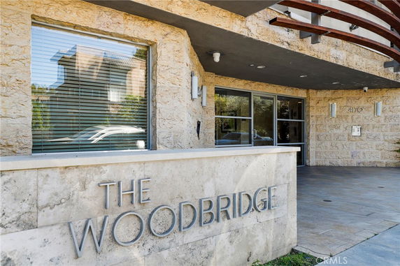 Exterior view of a building entrance with signage reading 'The Woodbridge' on a stone wall.