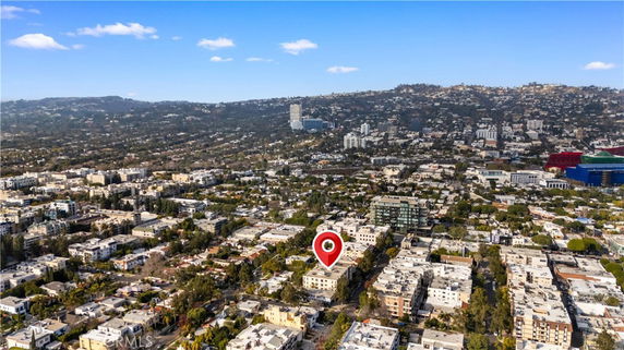 Aerial panoramic view of a cityscape with numerous buildings and hills in the background.