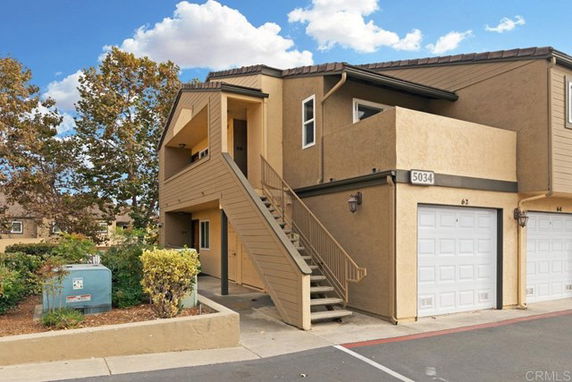 Front view of a two-story building with an external staircase and garages.