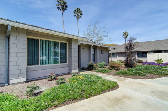 Front view of a single-story house with large windows and a well-manicured garden.