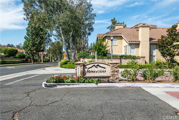Front view of a residential building with a sign for Montevista, surrounded by trees and road.