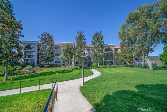 Front view of a multi-story building with a well-maintained green lawn and walkway.
