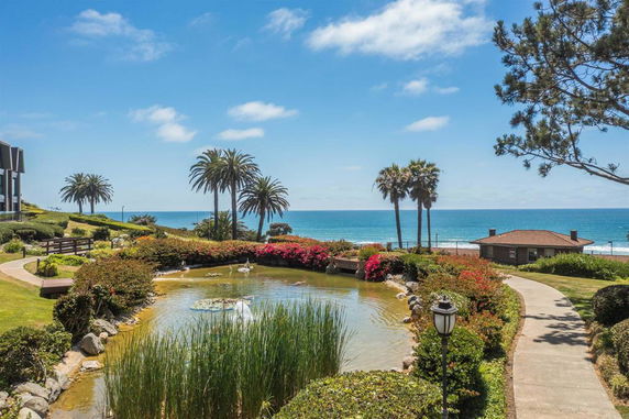 Scenic view of a garden pond with palm trees and ocean in the background.