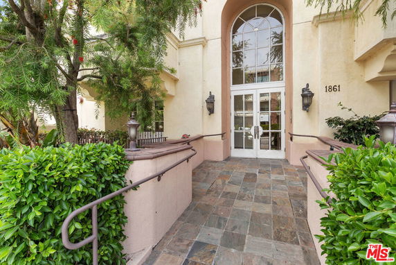 Front entrance of a building with large glass doors and a tiled pathway.