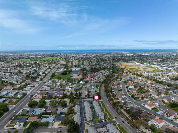 Aerial panoramic view showing a suburban area with residential houses, roads, and distant ocean.