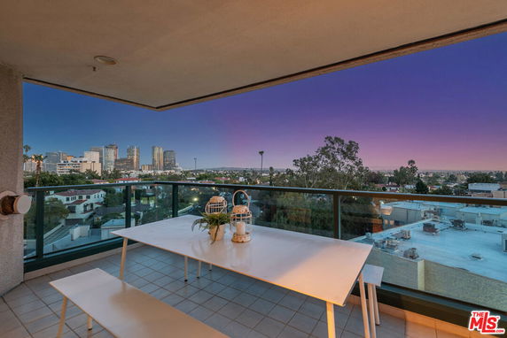 Panoramic view of the city skyline from a balcony with a table and benches.