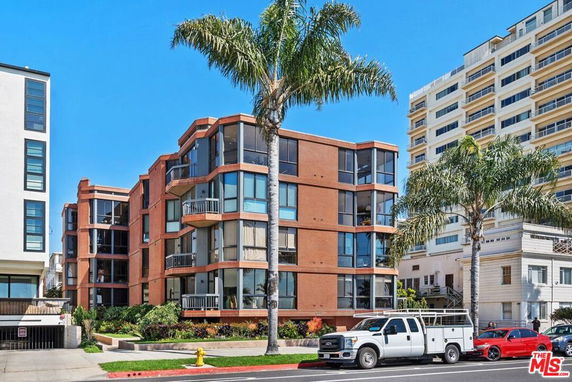 Front view of a modern multi-story brick apartment building with large windows and balconies.