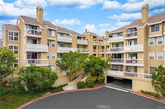 Front view of a multi-story residential building with balconies and a garage entrance.