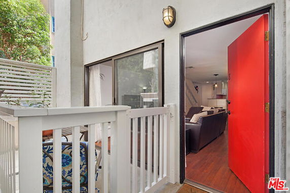 View of a building entrance with a red door and railing.