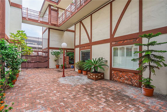 Exterior view of a multi-story building with a brick courtyard and potted plants.