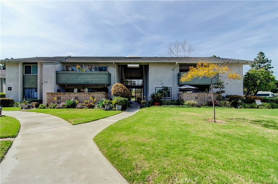 Front view of a two-story residential building with balconies and a central walkway.