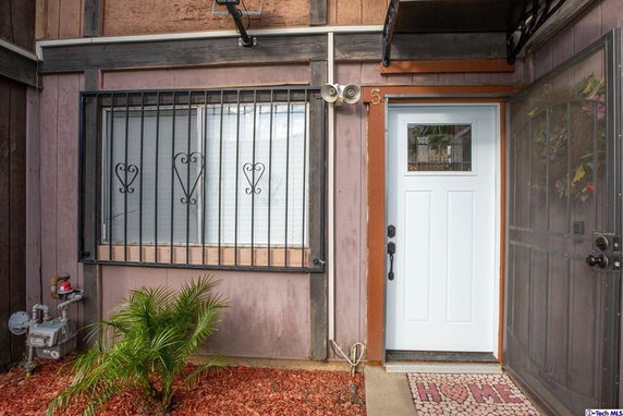 Front view of a house with a white door and barred window.