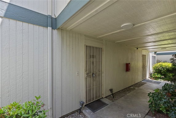 Covered entrance area of a building with a door and surrounding walls.