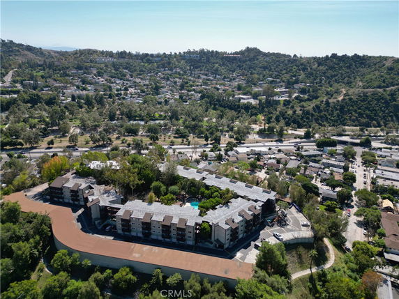 Aerial view of a multi-building complex with surrounding hilly area.