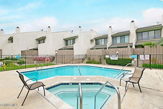 Outdoor swimming pool area with white residential buildings in the background.