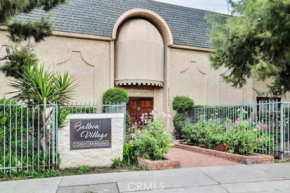 Front view of a condominium building with a gated entrance and landscaping.
