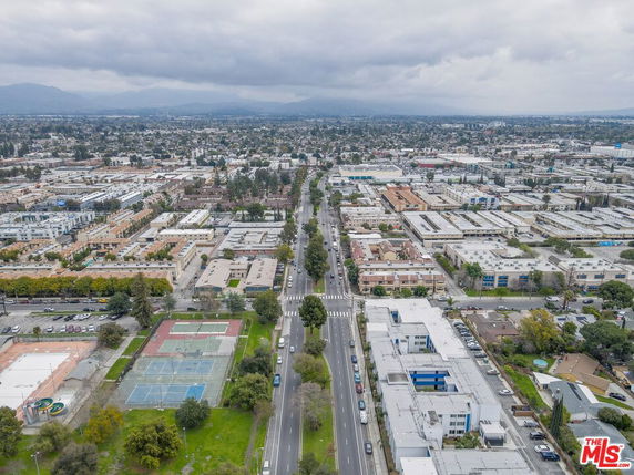 Aerial panoramic view of a city landscape with roads, buildings, and sports courts.