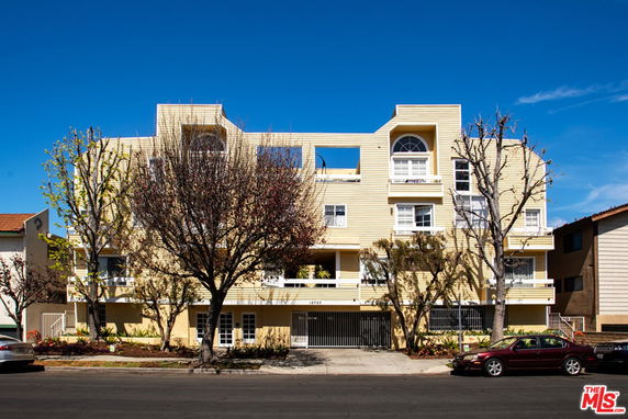 Front view of a multi-story residential building with yellow siding and multiple balconies.