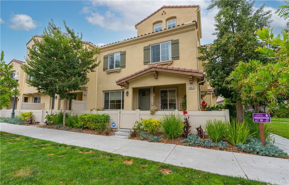 Front view of a multi-story townhouse with a tiled roof and small fenced garden.