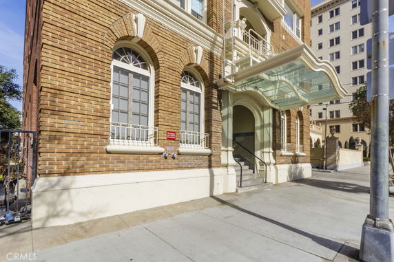 Front view of a brick building with arched windows and a glass canopy.
