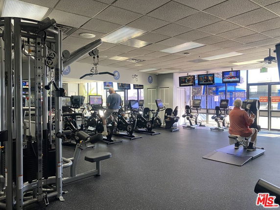 Indoor gym area with exercise equipment and people working out.