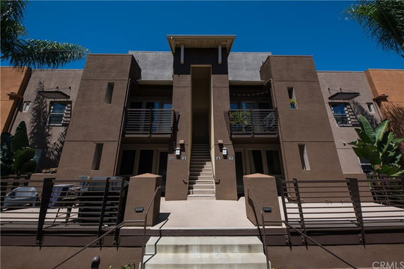 Front view of a multi-story building with balconies and central staircase.