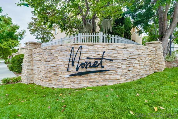 Stone wall with 'Monet' sign, part of a building's front view.