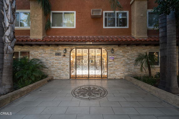 Front view of a multi-story building with decorative entry gate and tiled walkway.