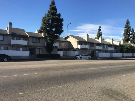 Front view of a row of two-story townhouses with chimneys and balconies.