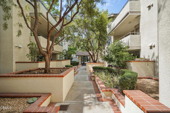 View of a multi-story building with a walkway and trees in the foreground.