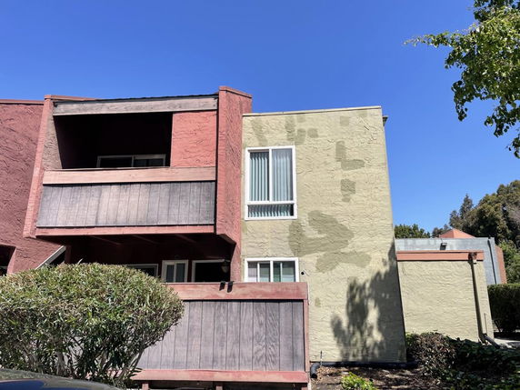 Front view of a two-story building with textured walls and balconies.