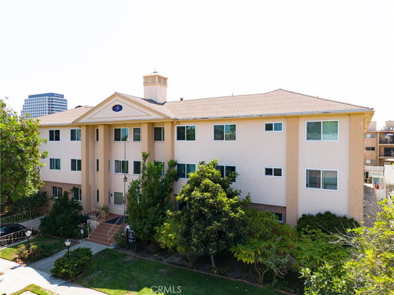 Front view of a three-story apartment building with a sloped roof and central entrance.