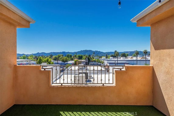 Panoramic view from a balcony showing rooftops and distant hills.