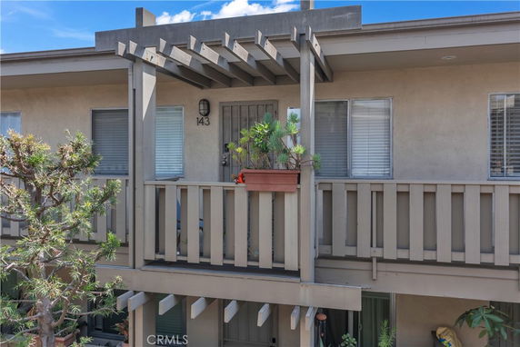 Front view of a two-story residential building with a small balcony and potted plants.