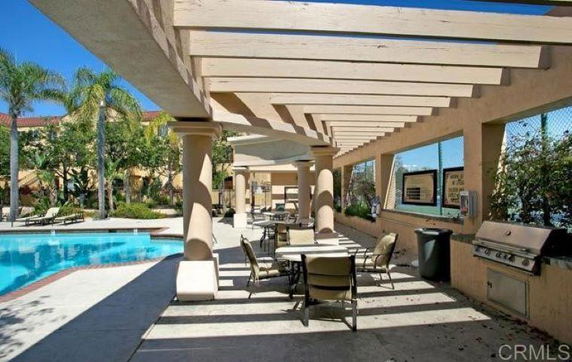Outdoor swimming pool area with pergola and seating.