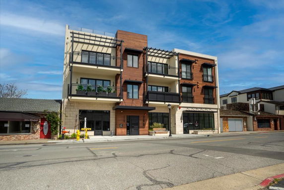 Front view of a modern, multi-story building with balconies and large windows.