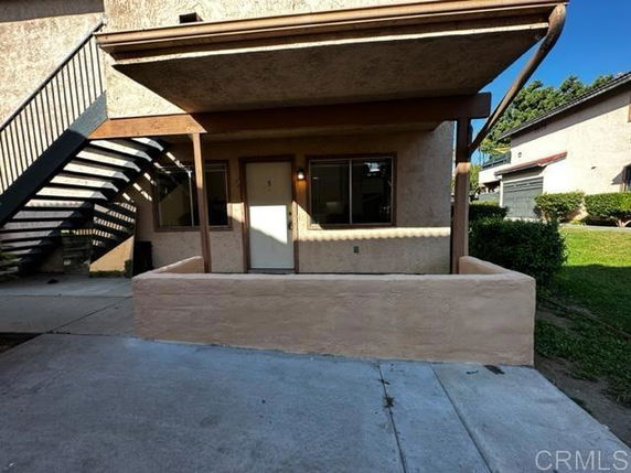 Front view of a ground-level apartment with a covered entrance and stairs leading to the upper floor.