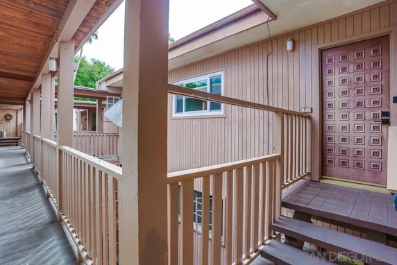 View of a building's exterior with a wooden walkway and entrance door.