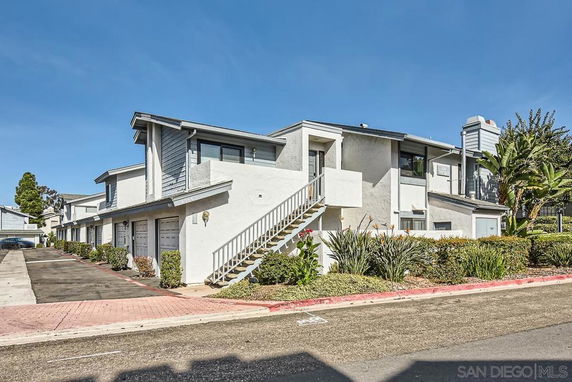 Front view of a multi-story residential building with garages and an exterior staircase.