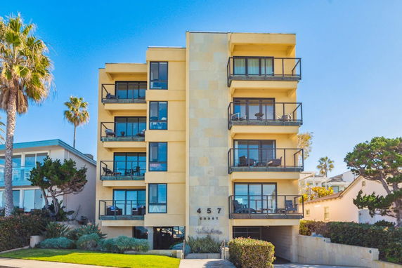 Front view of a modern multi-story apartment building with balconies and large windows.